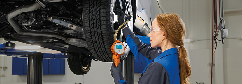 A Subaru technician checking tire pressure. | Thelen Subaru in Bay City MI